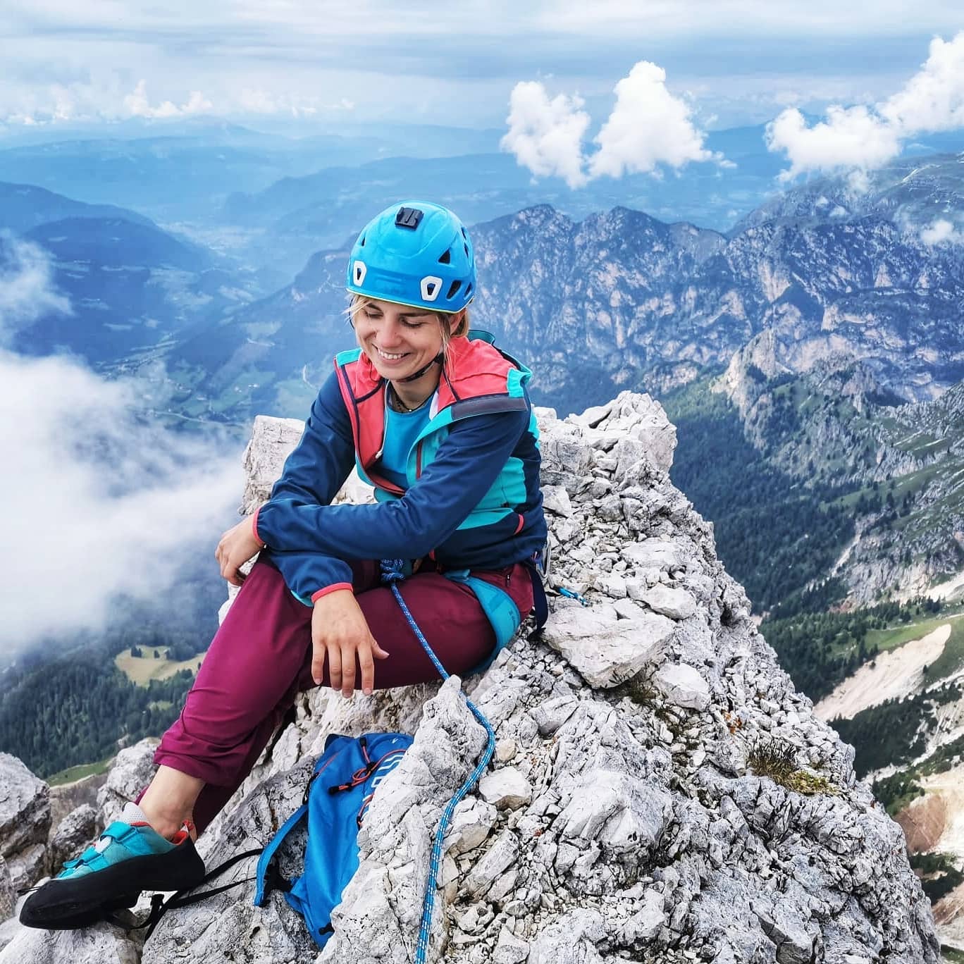 Foto di una ragazza che sorride seduta sulla cima di una montagna