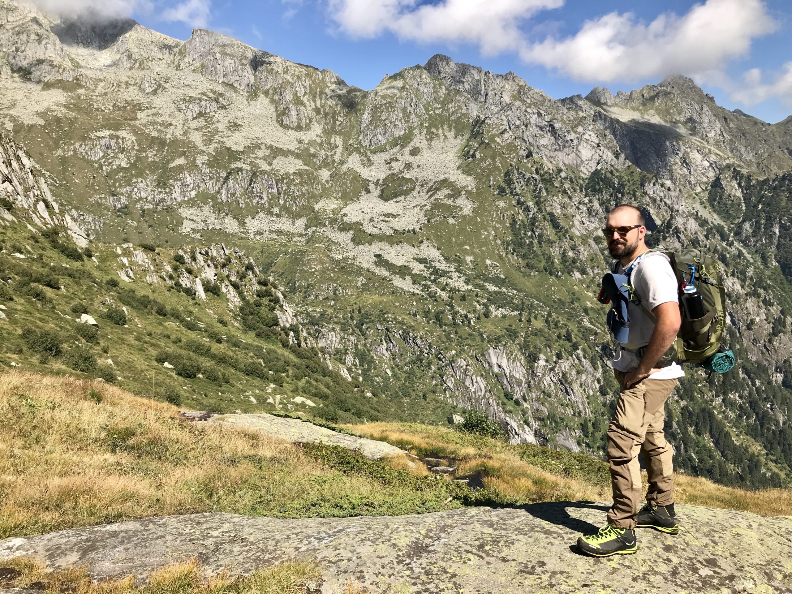 Foto di un ragazzo di fronte a delle montagne verdi e rocciose