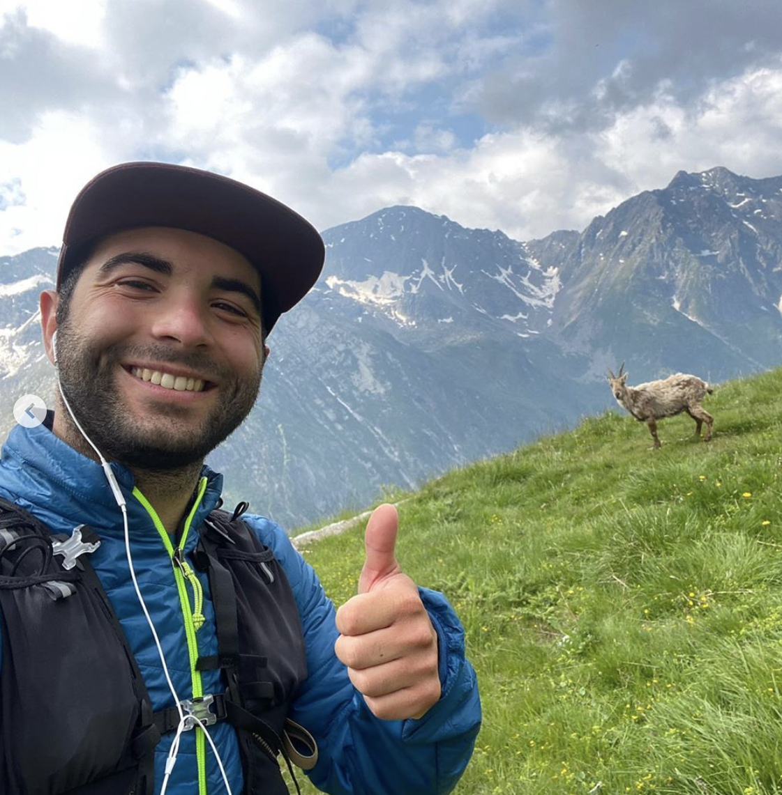 Foto di Davide, founder di Alps Platform, con una capra di fronte a delle montagne