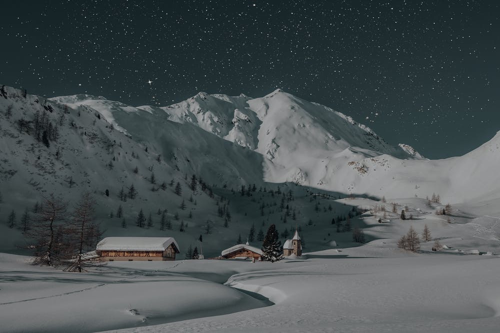 Vista montagne ricoperte di neve e dei rifugi con un cielo stellato