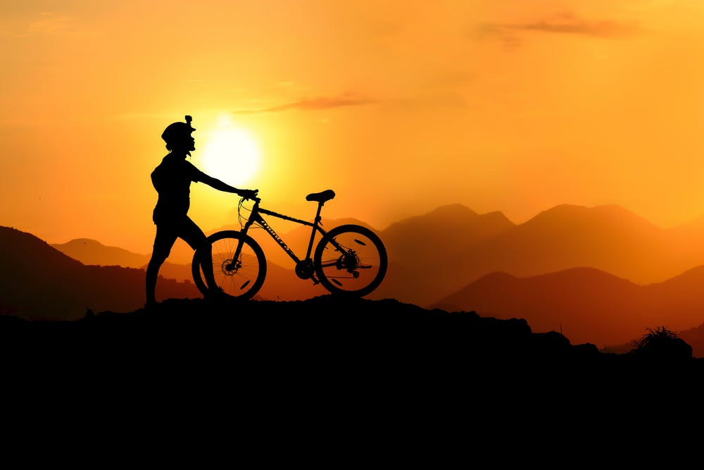 Vista tramonto delle montagne con un ragazzo e la sua bici