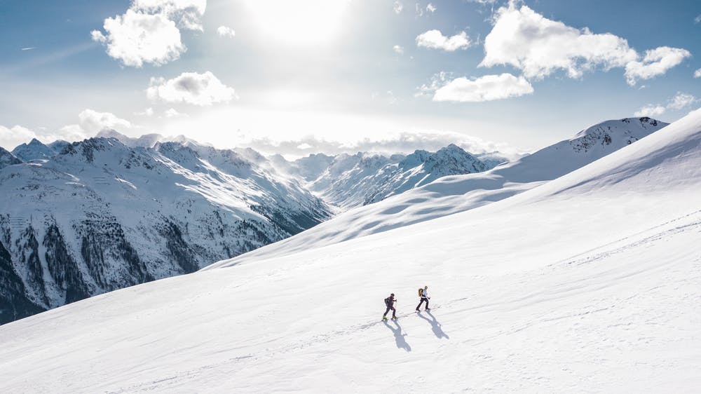 Vista montagne coperte di neve e due ragazzi che sciano